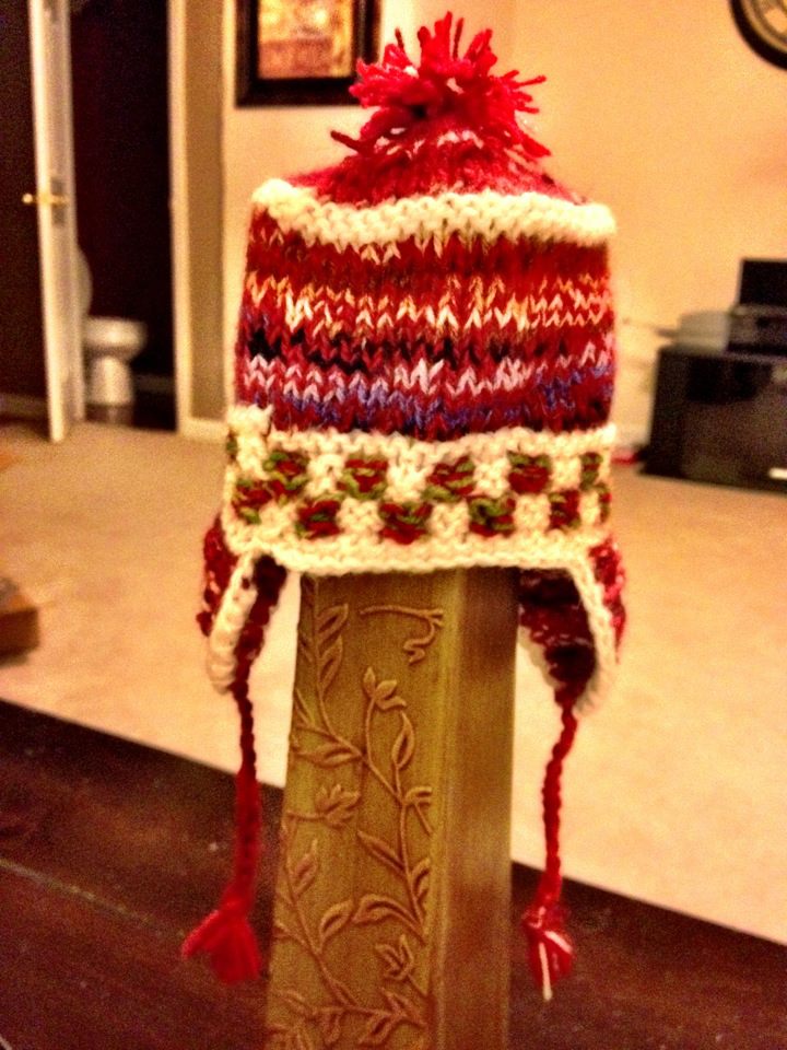 Red and cream knitted baby hat with ear flaps and tassels
